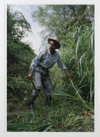 Jonathan Moller, Santiago clears the brush before digging begins where he and others believe the remains of a relative killed by the army are buried, type C color print, 20 x 16 inches, edition # 3/25